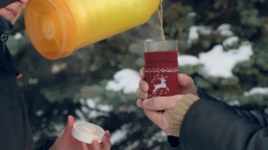 Kadın ormanda, güzel kış manzara karlı köknar ağaçları ile sıcak çay içiyor.