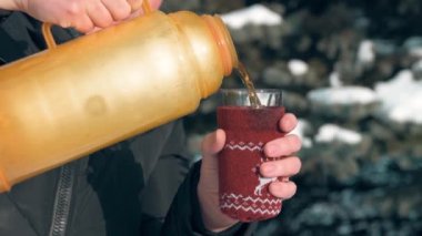 Kadın ormanda, güzel kış manzara karlı köknar ağaçları ile sıcak çay içiyor.