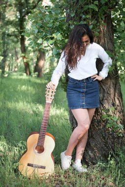 ormanda yürüyüş ve iskambil gitar, yaz doğa, parlak güneş ışığı, gölgeler ve yeşil yaprakları, romantik duygular genç kadın