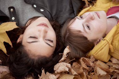 Güzel kadın ve Genç kız sonbahar parkta poz olan. Düşen yapraklar üzerinde yalan söylüyorsun. Sonbahar sezonu, güzel manzara.