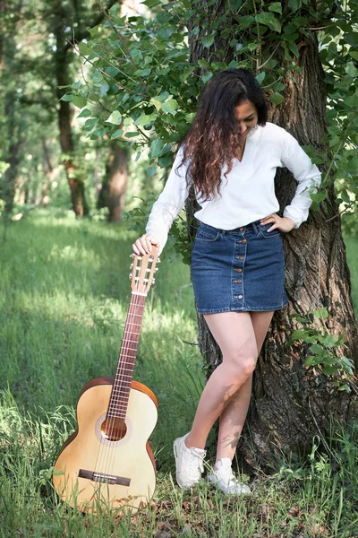 ormanda yürüyüş ve iskambil gitar, yaz doğa, parlak güneş ışığı, gölgeler ve yeşil yaprakları, romantik duygular genç kadın