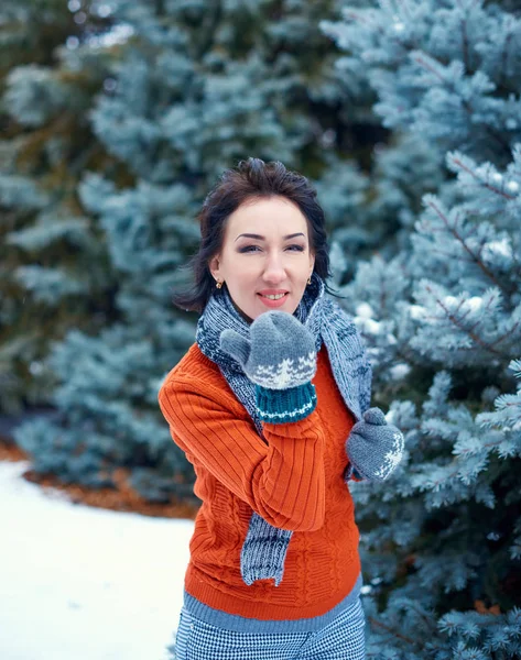妇女是在冬季森林中摆姿势 美丽的风景与雪杉树 穿着红色毛衣 吹一个吻 — 图库照片