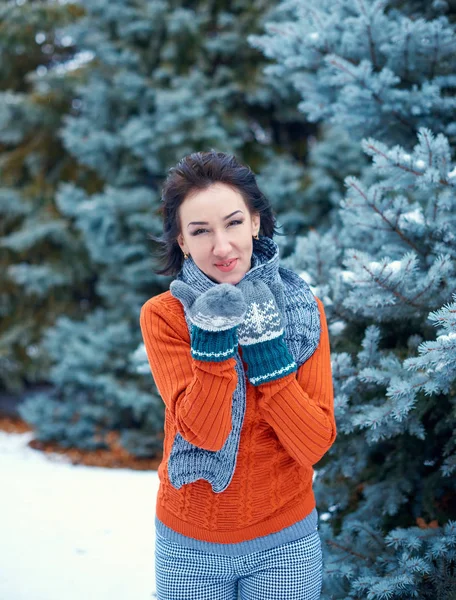 妇女是在冬季森林中摆姿势 美丽的风景与雪杉树 穿着红色毛衣 吹一个吻 — 图库照片