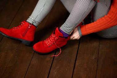 Beautiful woman gets red shoes. Dark wooden background. Dressed in red knitted hat and sweater.