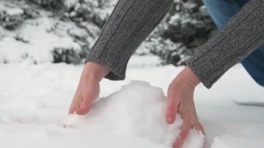 Kadın kar avuç alır ve bir kartopu kılan, gands yakın. Karlı köknar ağaçları ile güzel manzara