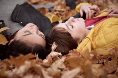 Güzel kadın ve Genç kız sonbahar parkta poz olan. Düşen yapraklar üzerinde yalan söylüyorsun. Sonbahar sezonu, güzel manzara.