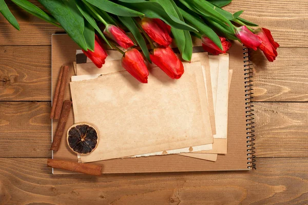 Ramo de tulipán está sobre fondo de madera, hojas viejas de papel en blanco para el texto, estilo retro —  Fotos de Stock