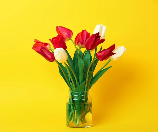 Tulp bloemen zijn in een vaas op gele achtergrond — Stockfoto