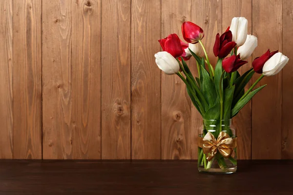 Fleurs de tulipe sont dans un vase, fond en bois — Photo