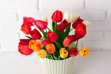 Lale çiçek masada beyaz tuğla duvar arka plan olarak bir sepet içinde vardır
