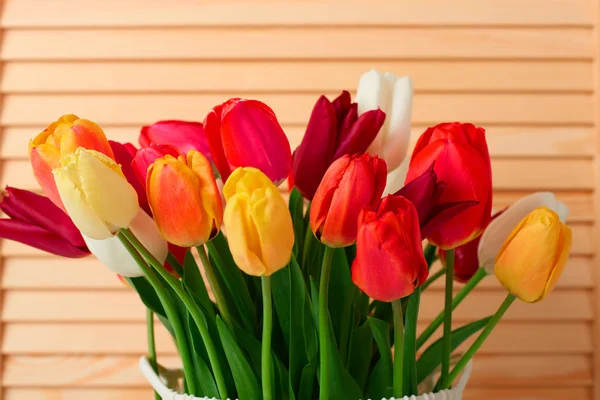 Flores de tulipán están en una cesta sobre la mesa, fondo de madera — Foto de Stock