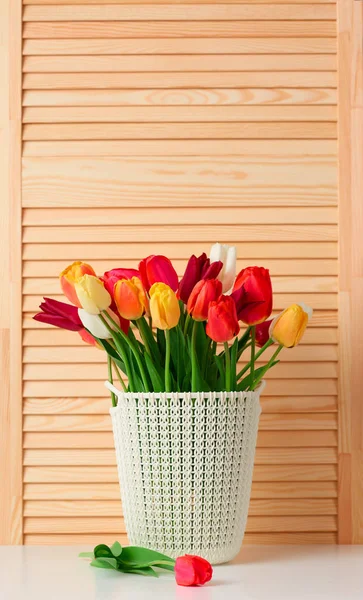 チューリップの花は、テーブルの木材の背景上バスケット — ストック写真