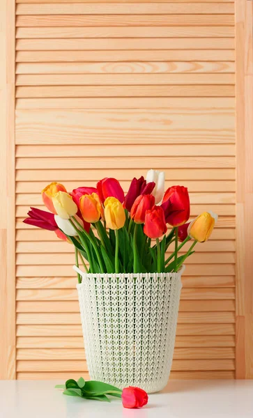 Flores de tulipán están en una cesta sobre la mesa, fondo de madera — Foto de Stock