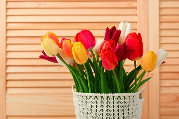 Flores de tulipán están en una cesta sobre la mesa, fondo de madera — Foto de Stock