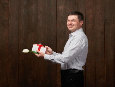 Adam bir hediye kutusu ve Beyaz Lale çiçek tutan