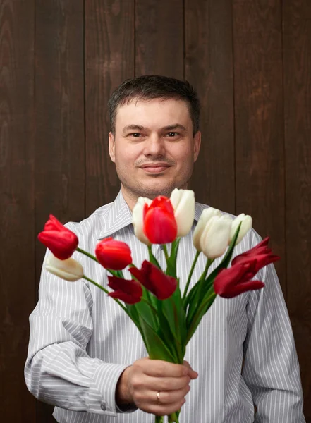 Man håller röda blommor bukett — Stockfoto