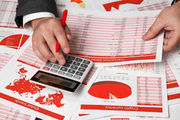 Businessman accountant using calculator for calculating cryptocurrency report on desk office. Business financial accounting concept. Red reports and graphs. — Stock Photo, Image
