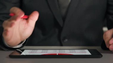 Bir tablet üzerinde çalışan işadamı grafikler ve tablolar çözümler, closeup eller.