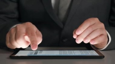 Bir tablet üzerinde çalışan işadamı grafikler ve tablolar çözümler, closeup eller.