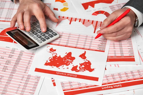 Contador del hombre de negocios utilizando la calculadora para calcular las finanzas en la oficina de escritorio. Concepto de contabilidad financiera empresarial Informes y gráficos rojos. Empleado de oficina examina horarios e informes . — Foto de Stock