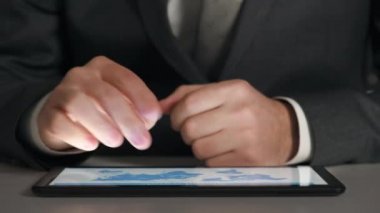 Bir tablet üzerinde çalışan işadamı grafikler ve tablolar çözümler, closeup eller.