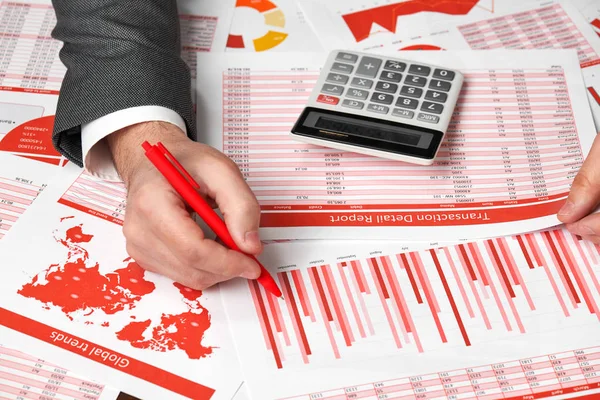 Contador del hombre de negocios utilizando la calculadora para calcular las finanzas en la oficina de escritorio. Concepto de contabilidad financiera empresarial Informes y gráficos rojos. Empleado de oficina examina horarios e informes . — Foto de Stock