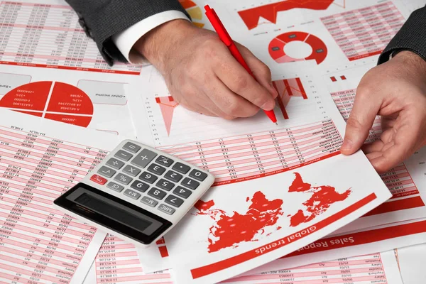 Contador del hombre de negocios utilizando la calculadora para calcular las finanzas en la oficina de escritorio. Concepto de contabilidad financiera empresarial Informes y gráficos rojos. Empleado de oficina examina horarios e informes . — Foto de Stock