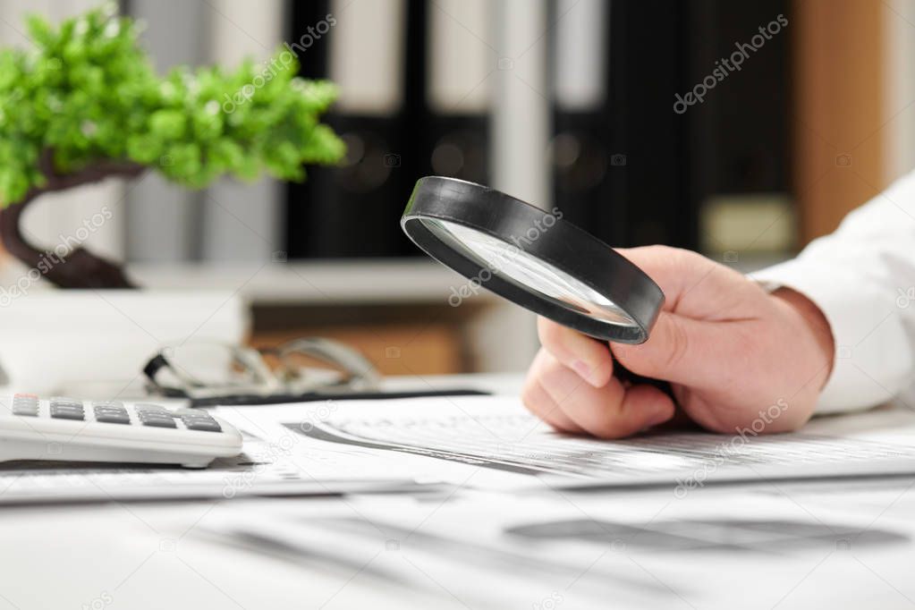 Businessman working in office and calculating finance. Using magnifying glass. Business financial accounting concept.