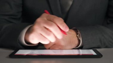 Bir tablet üzerinde çalışan işadamı grafikler ve tablolar çözümler, closeup eller.