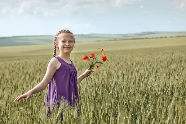 Flicka med röd tulpan blommor poserar i vetefält, strålande sol, vackra sommarlandskap — Stockfoto