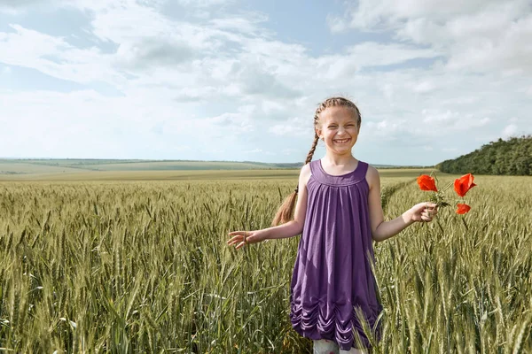 Fille avec des fleurs de tulipe rouge posant dans le champ de blé, soleil brillant, beau paysage d'été — Photo