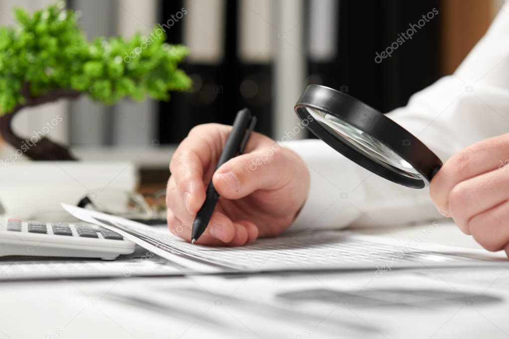 Businessman working in office and calculating finance. Using magnifying glass. Business financial accounting concept.