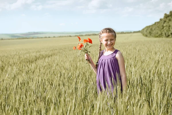 Ragazza con fiori di tulipano rosso in posa nel campo di grano, sole luminoso, bellissimo paesaggio estivo — Foto Stock