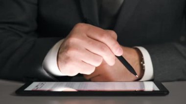 Bir tablet üzerinde çalışan işadamı grafikler ve tablolar çözümler, closeup eller.