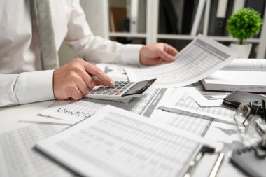 Ofiste çalışan ve finans hesaplaması yapan işadamı, raporları okur ve yazar. İş mali muhasebe kavramı.