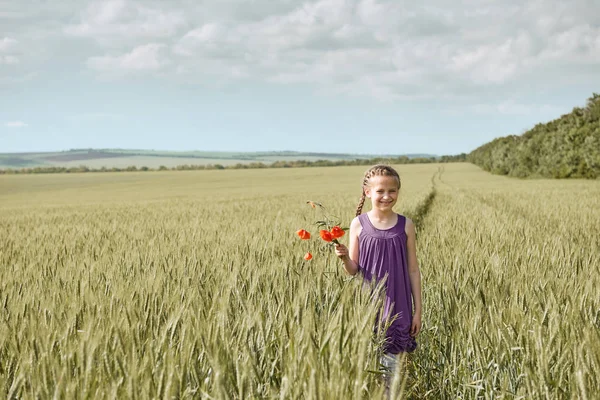 麦畑、明るい太陽の下、美しい夏の風景でポーズの赤いチューリップの花を持つ少女 — ストック写真