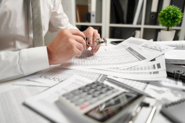 Ofiste çalışan ve finans hesaplaması yapan işadamı, raporları okur ve yazar. İş mali muhasebe kavramı.