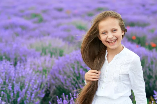 Menina criança está no campo de flores de lavanda, bela paisagem de verão — Fotografia de Stock