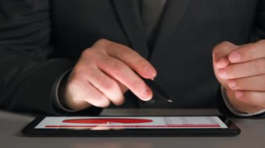 Bir tablet üzerinde çalışan işadamı grafikler ve tablolar çözümler, closeup eller.