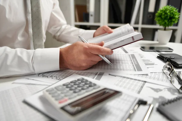 Biznesmen pracujący w biurze i obliczając finanse, czyta i pisze raporty. Koncepcja rachunkowości finansowej firmy. — Zdjęcie stockowe