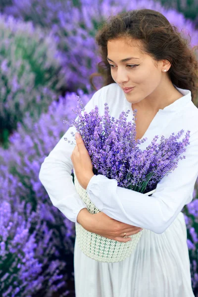 Mujer joven está en el campo de flores de lavanda, hermoso paisaje de verano — Foto de Stock