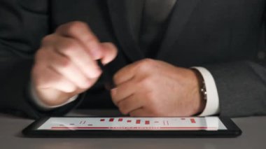 Bir tablet üzerinde çalışan işadamı grafikler ve tablolar çözümler, closeup eller.