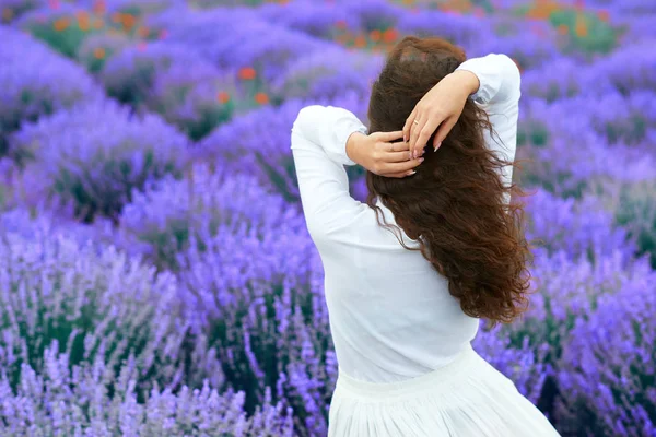 Mladá žena stojí vzadu v levandulové květinové oblasti, krásná letní krajina — Stock fotografie