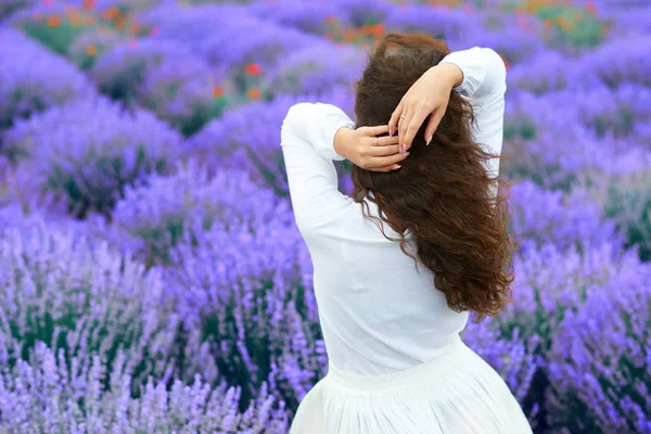 Mladá žena stojí vzadu v levandulové květinové oblasti, krásná letní krajina — Stock fotografie