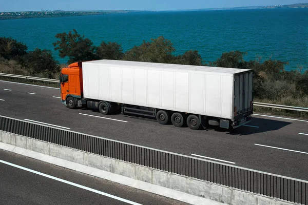 Un camión blanco está subiendo la carretera cerca del mar. Concepto de transporte de carga . — Foto de Stock