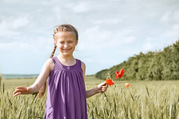 Flicka med röd tulpan blommor poserar i vetefält, strålande sol, vackra sommarlandskap — Stockfoto