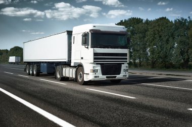 Beyaz kamyon yolun yukarısına gidiyor. Kargo taşımacılığı kavramı.
