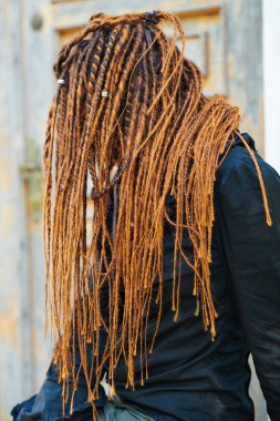 dreadlocks moda kız eski ahşap kapı arka planda poz. yüzü görünmeyen yan görünüm