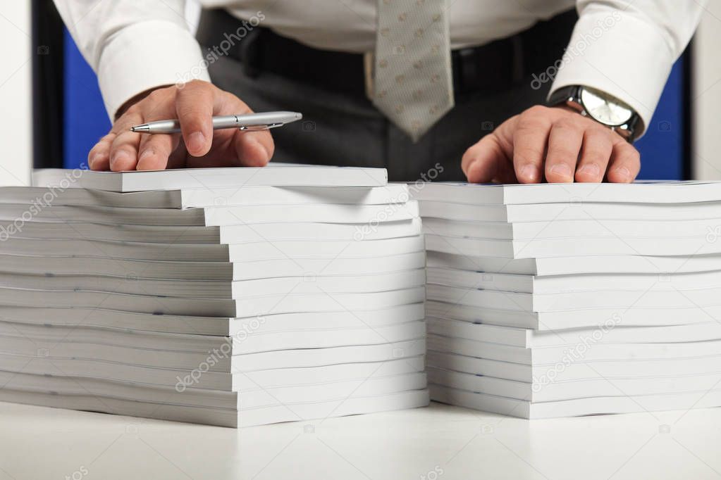 Businessman working at an office, reads stack of books and reports. Business financial accounting concept.