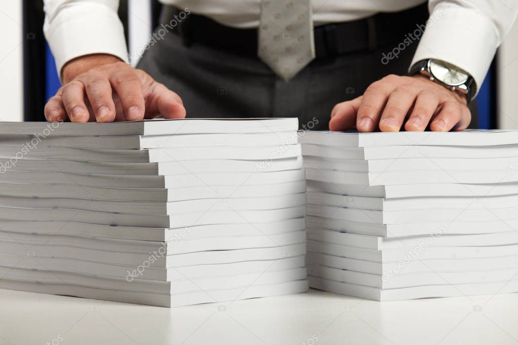 Businessman working at an office, reads stack of books and reports. Business financial accounting concept.